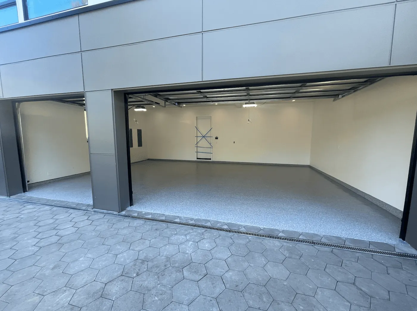 Modern Seattle-area building's garage bay with a pearl flake floor behind hexagon pavers