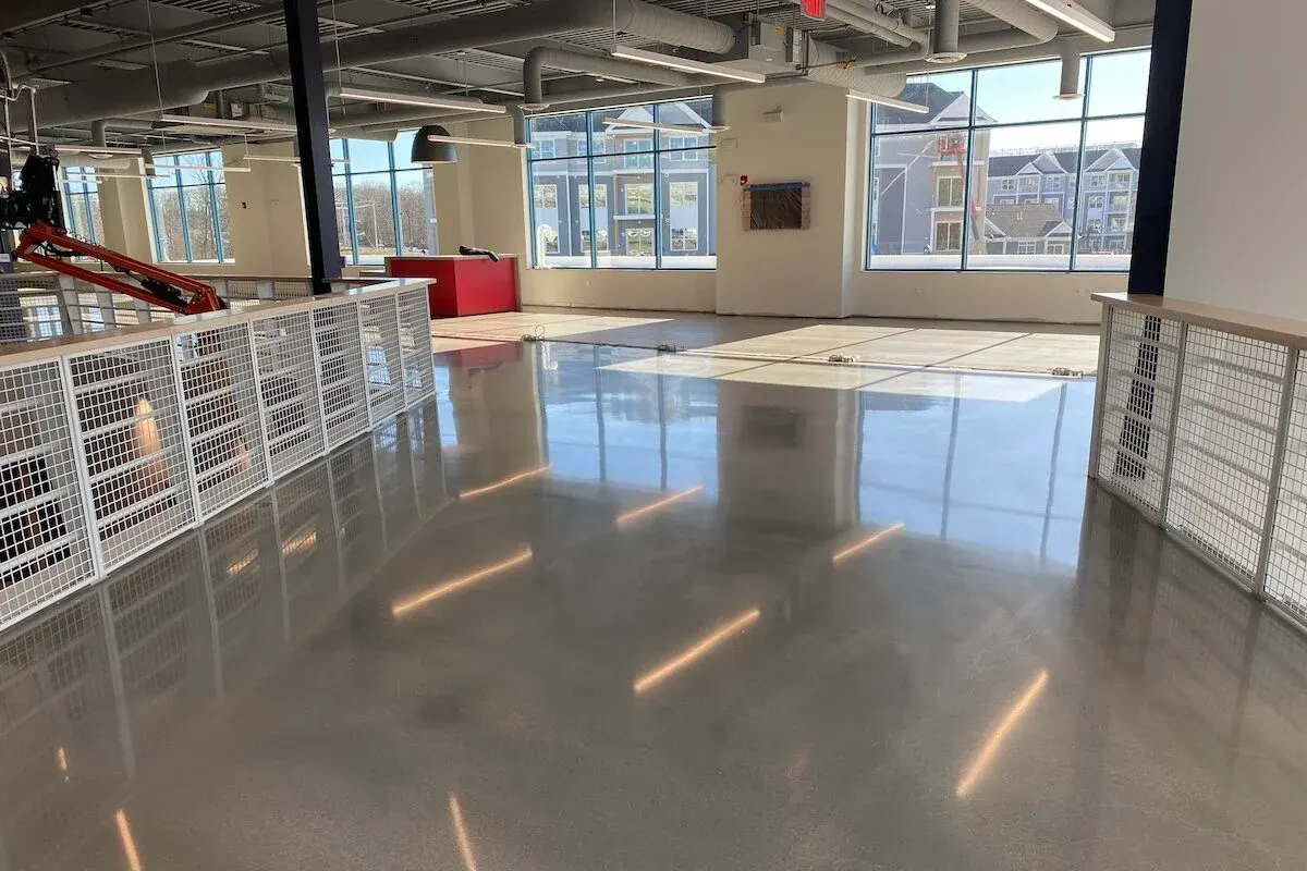 Open commercial loft with a high-gloss gray floor, wire-mesh railings and tall windows