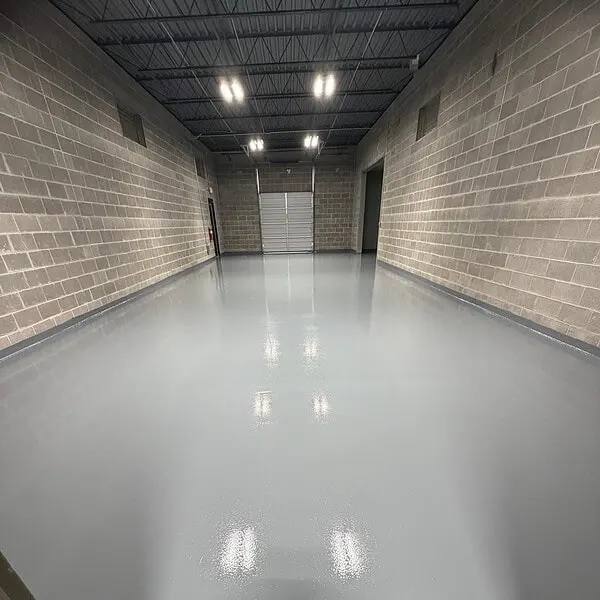 Block-walled corridor with a glossy light gray floor leading to an overhead door