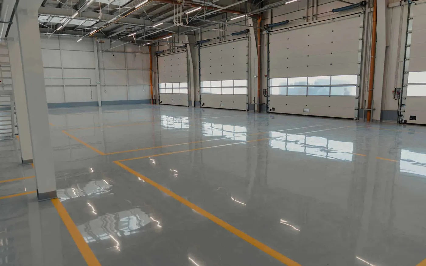Empty vehicle bays with a glossy gray floor and yellow safety striping