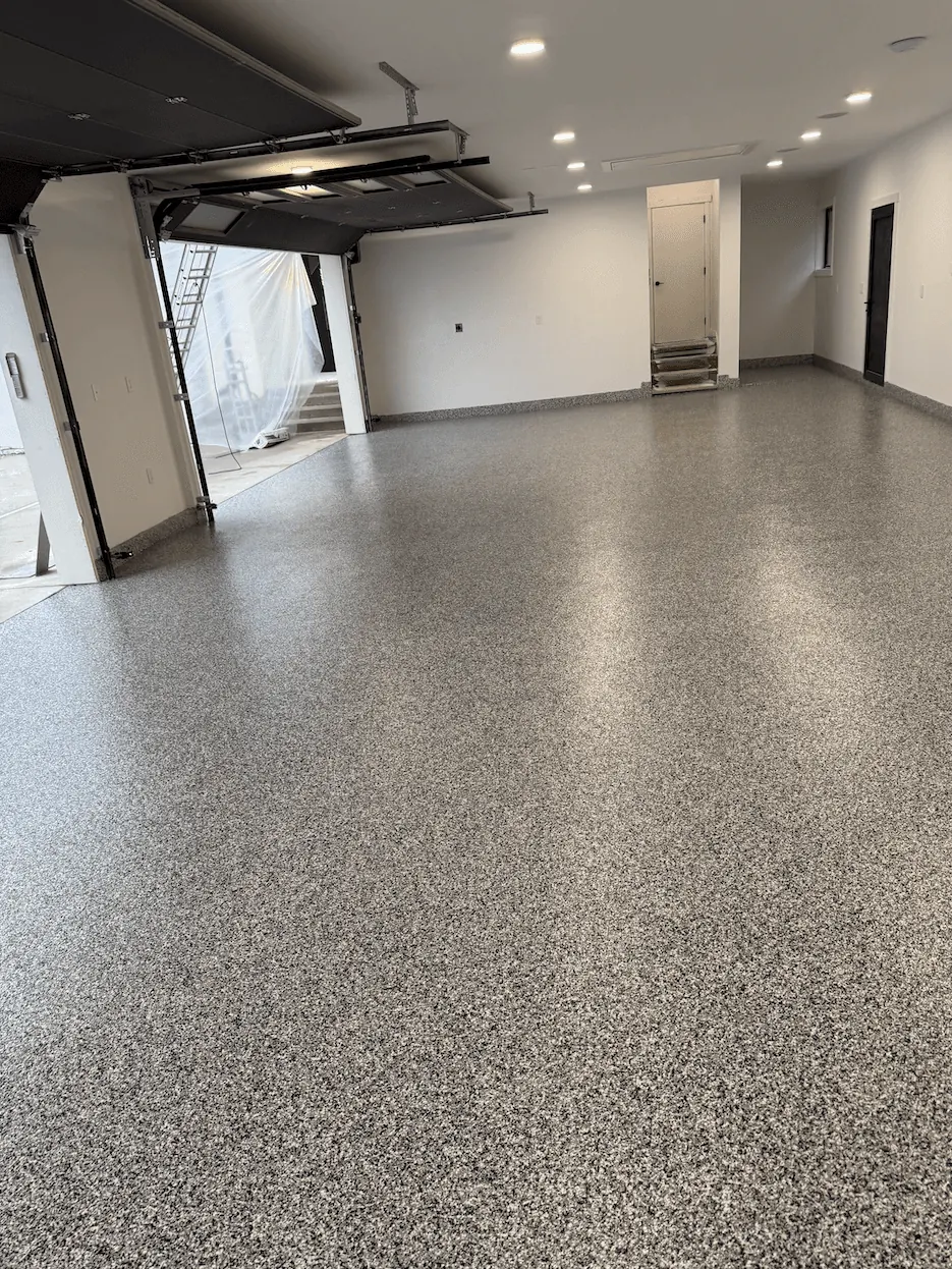 Ash flake floor in a Seattle-area garage with recessed lights and steps up to an interior door