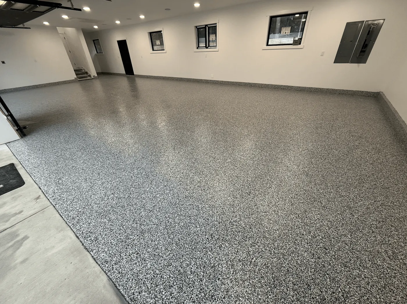 Salt-and-pepper ash full-flake garage floor coating in a Seattle-area garage beneath high windows