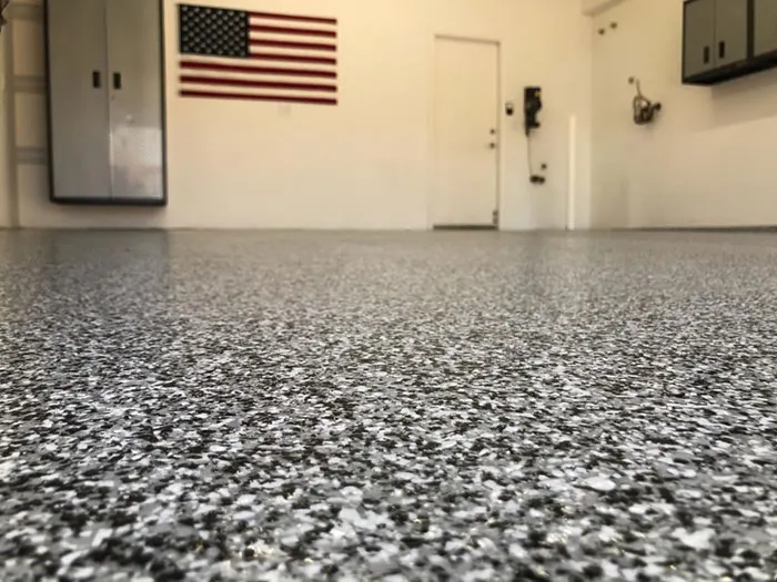 Low-angle view of a black, white and gray flake garage floor below a wall-mounted American flag