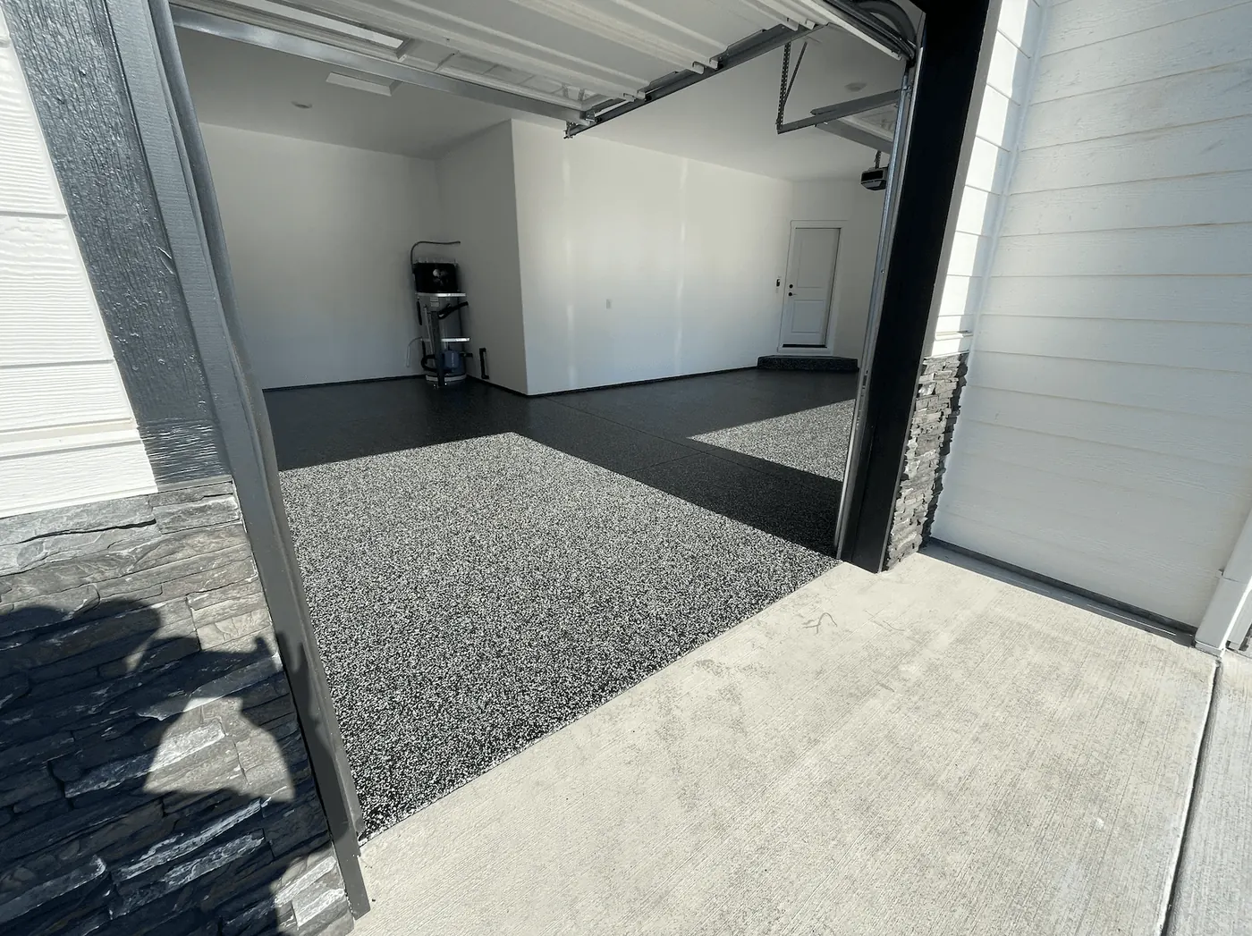 Charcoal flake garage floor in a Seattle-area home, framed by a stone-trimmed door opening
