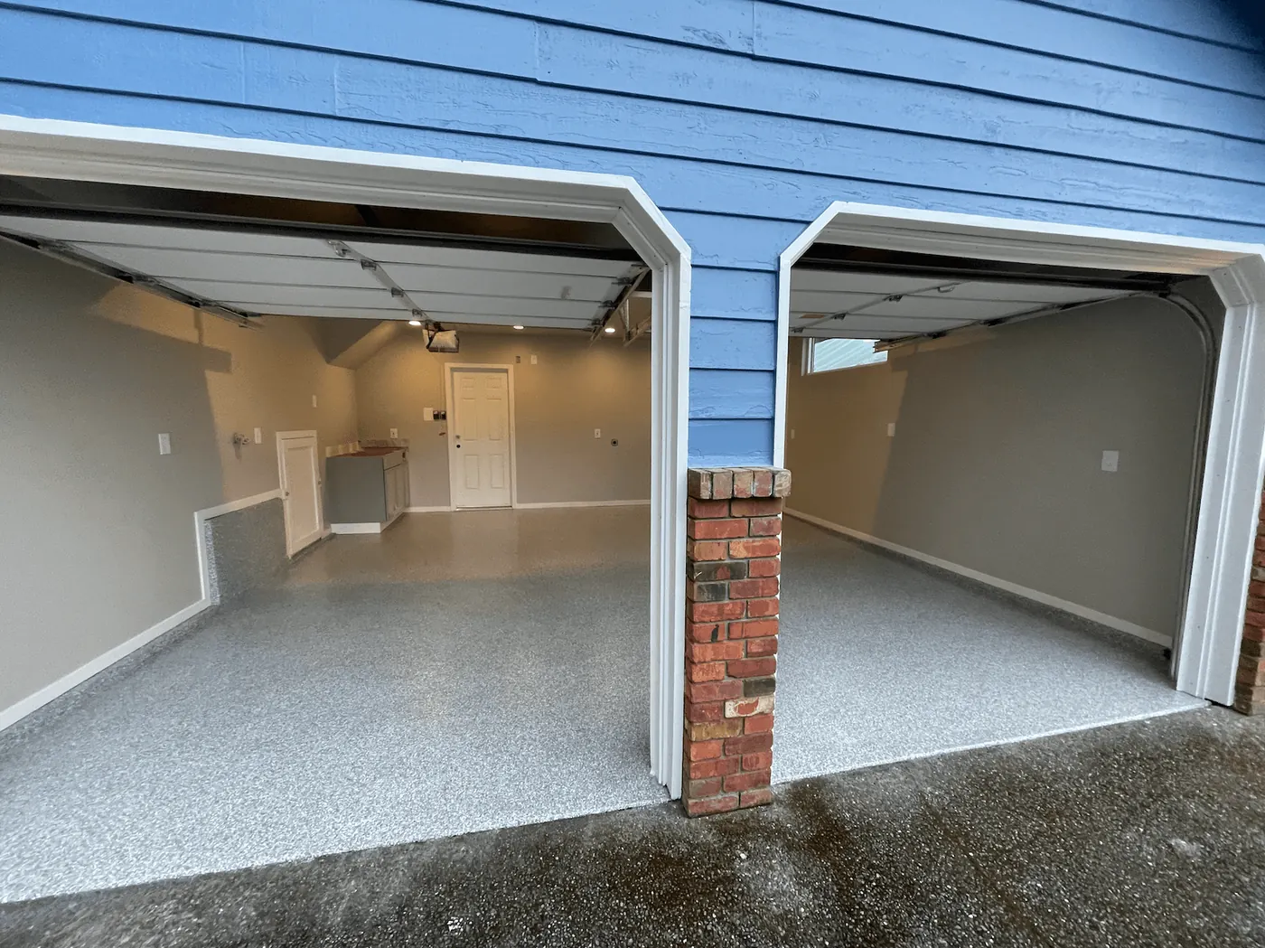 Blue Seattle-area house with two single garage doors open to a silver granite flake floor