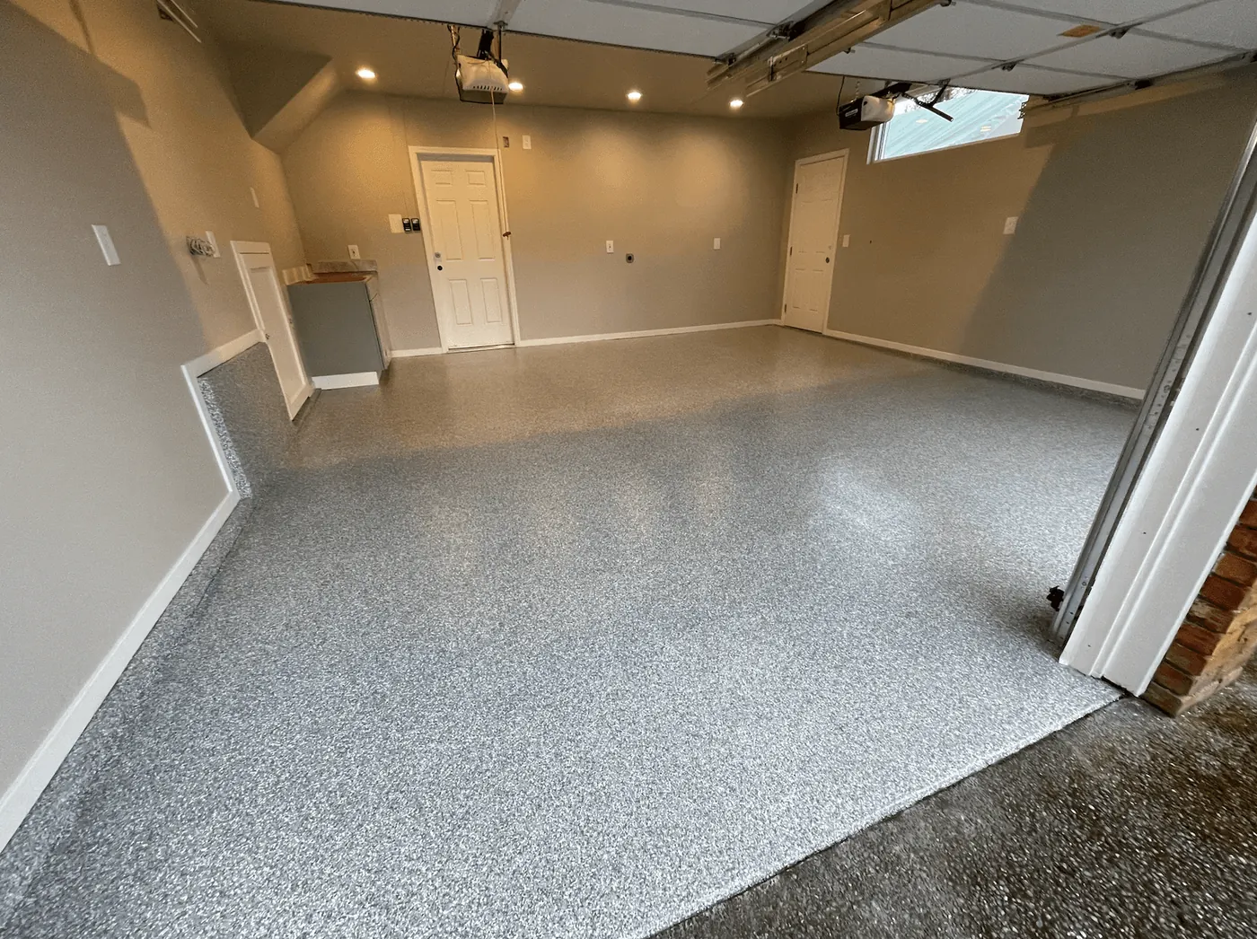Seattle-area two-car garage with a silver granite flake floor under warm recessed lighting