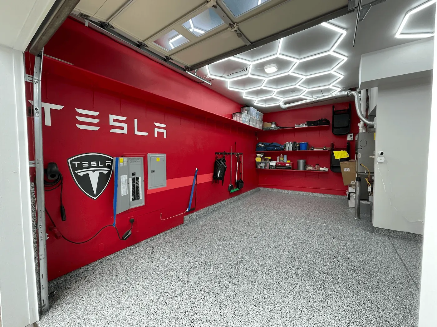 Red Tesla accent wall and hexagon lighting over a storm gray flake floor in a Seattle-area garage
