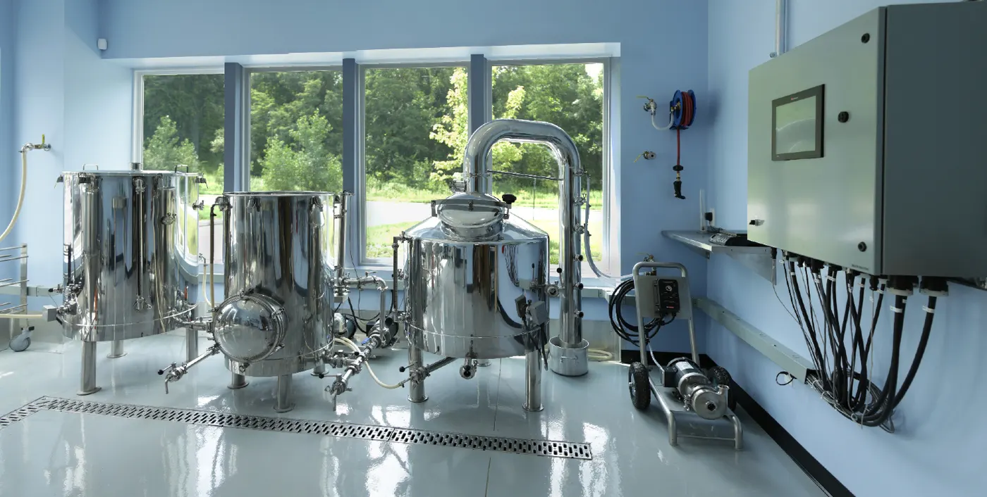 Stainless steel processing tanks on a glossy light gray floor with a trench drain