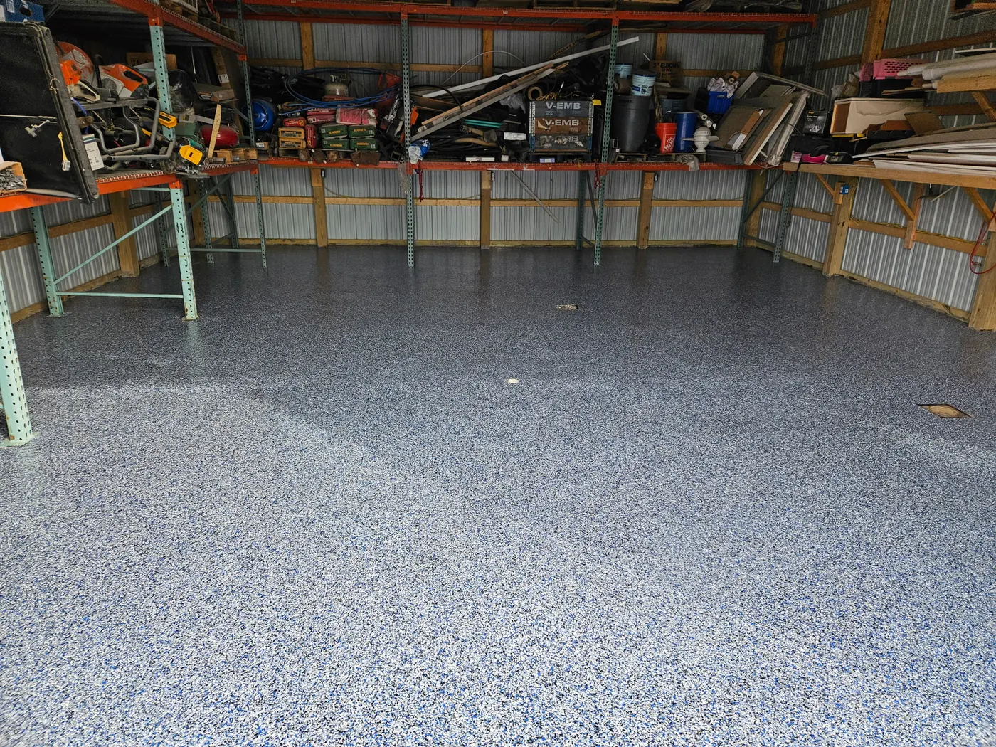Pole-building workshop with a slate blue flake floor and loaded tool shelves