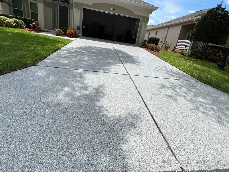 Residential driveway with a light gray flake coating leading to a two-car garage