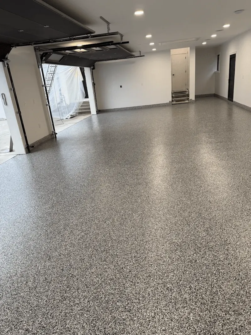 Ash flake floor in a Seattle-area garage with recessed lights and steps up to an interior door