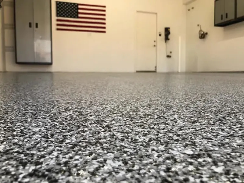 Low-angle view of a black, white and gray flake garage floor below a wall-mounted American flag