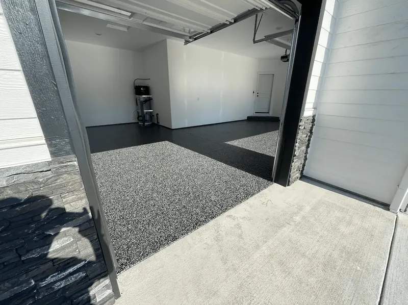Charcoal flake garage floor in a Seattle-area home, framed by a stone-trimmed door opening