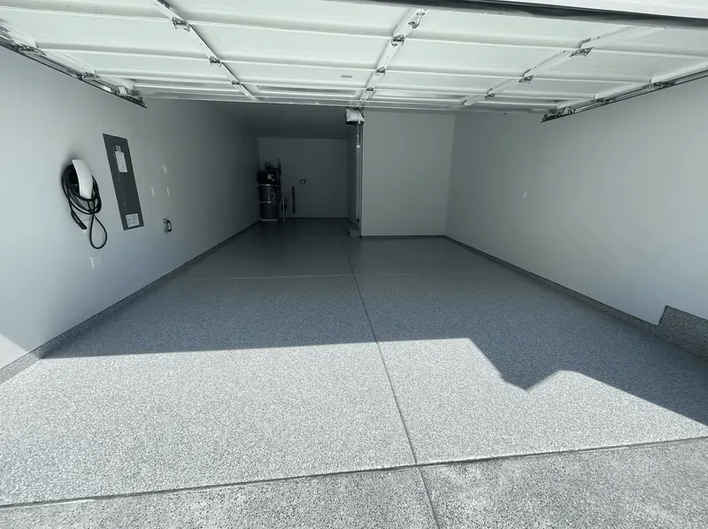 Sunlit platinum flake floor under a raised door in a Seattle-area garage with an EV charger