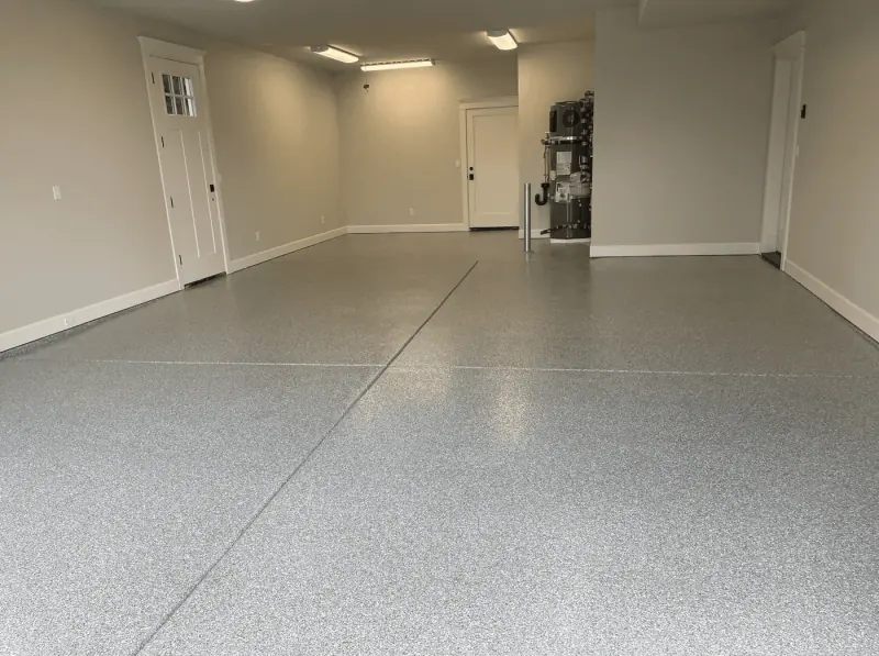 Long garage with a silver flake floor and white paneled doors
