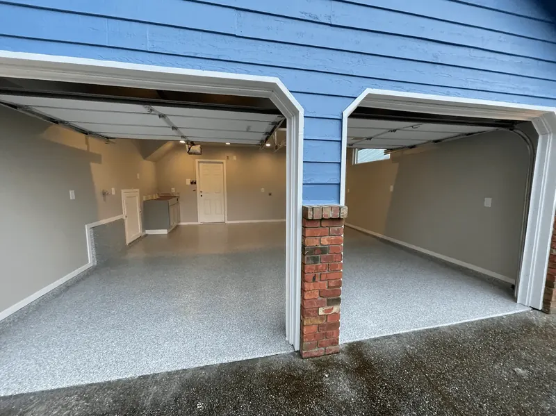Blue Seattle-area house with two single garage doors open to a silver granite flake floor
