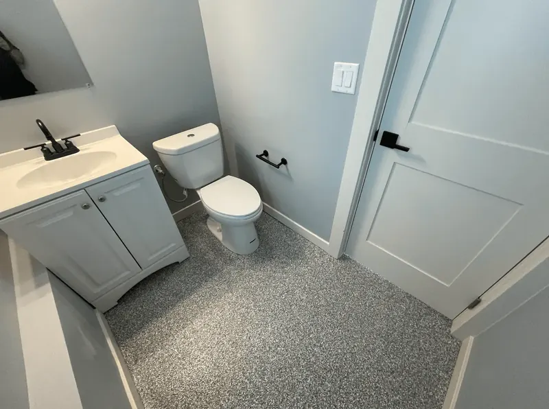 Small bathroom with a gray flake floor coating, white vanity and toilet