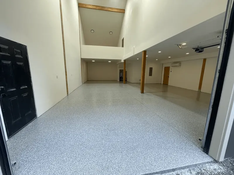 Open shop with a granite flake floor, seen through a black entry door