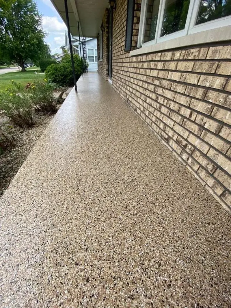 Covered front walkway along a brick house with a tan flake coating